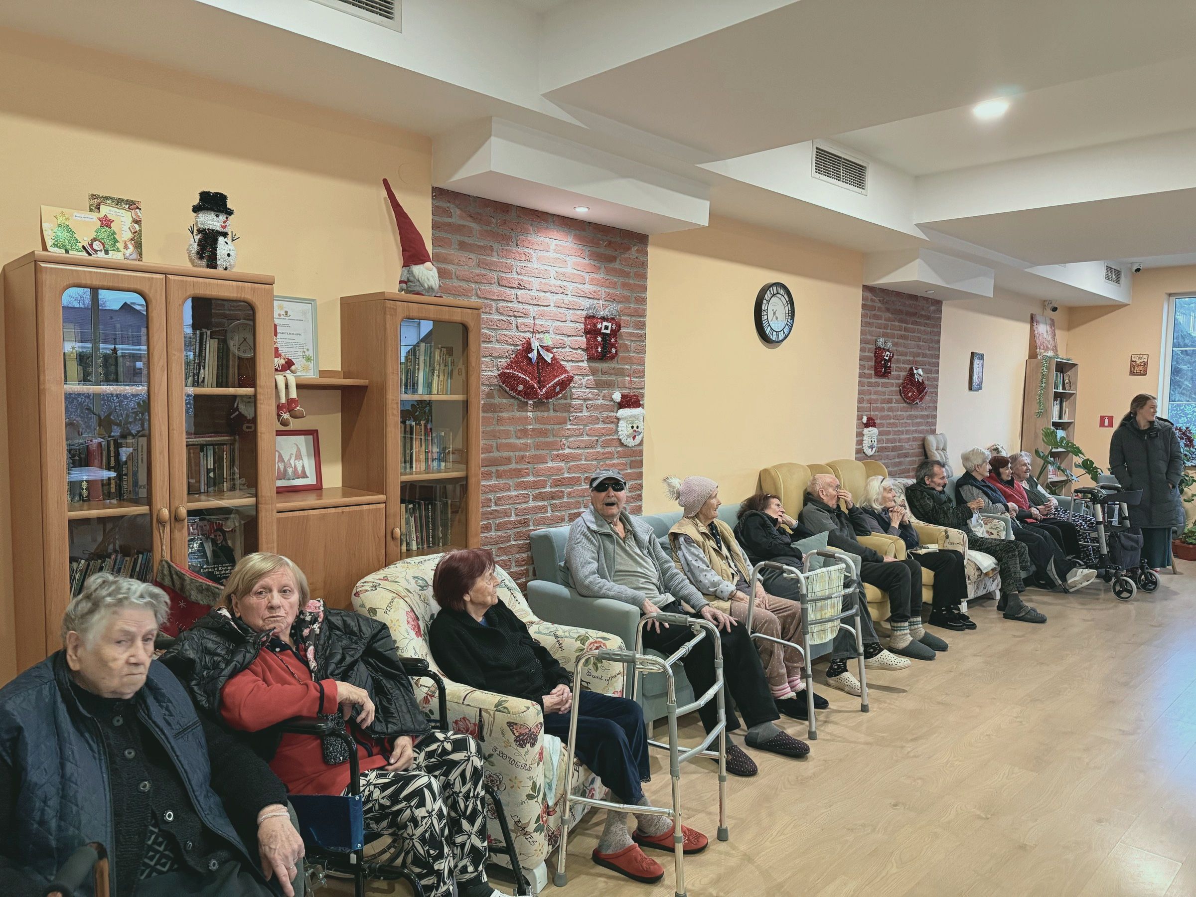 Настанените в дома, събрани в украсената за Коледа дневна преди концерта
